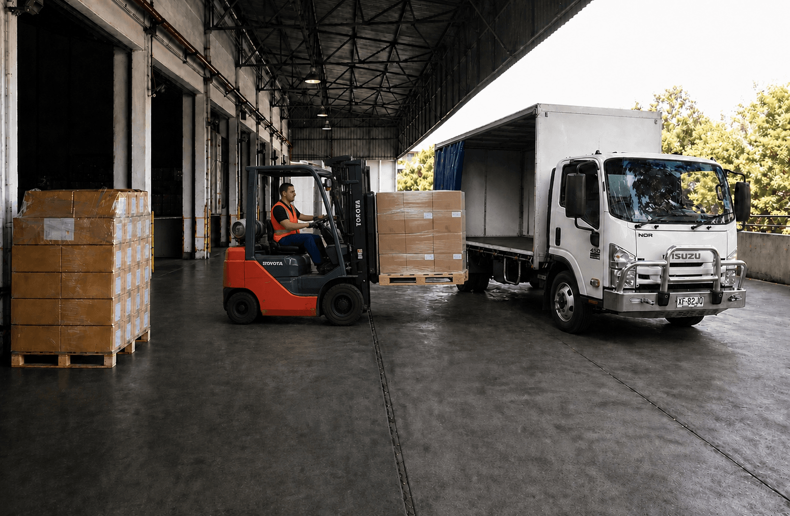 Forklift loading palletised freight onto a truck at a warehouse